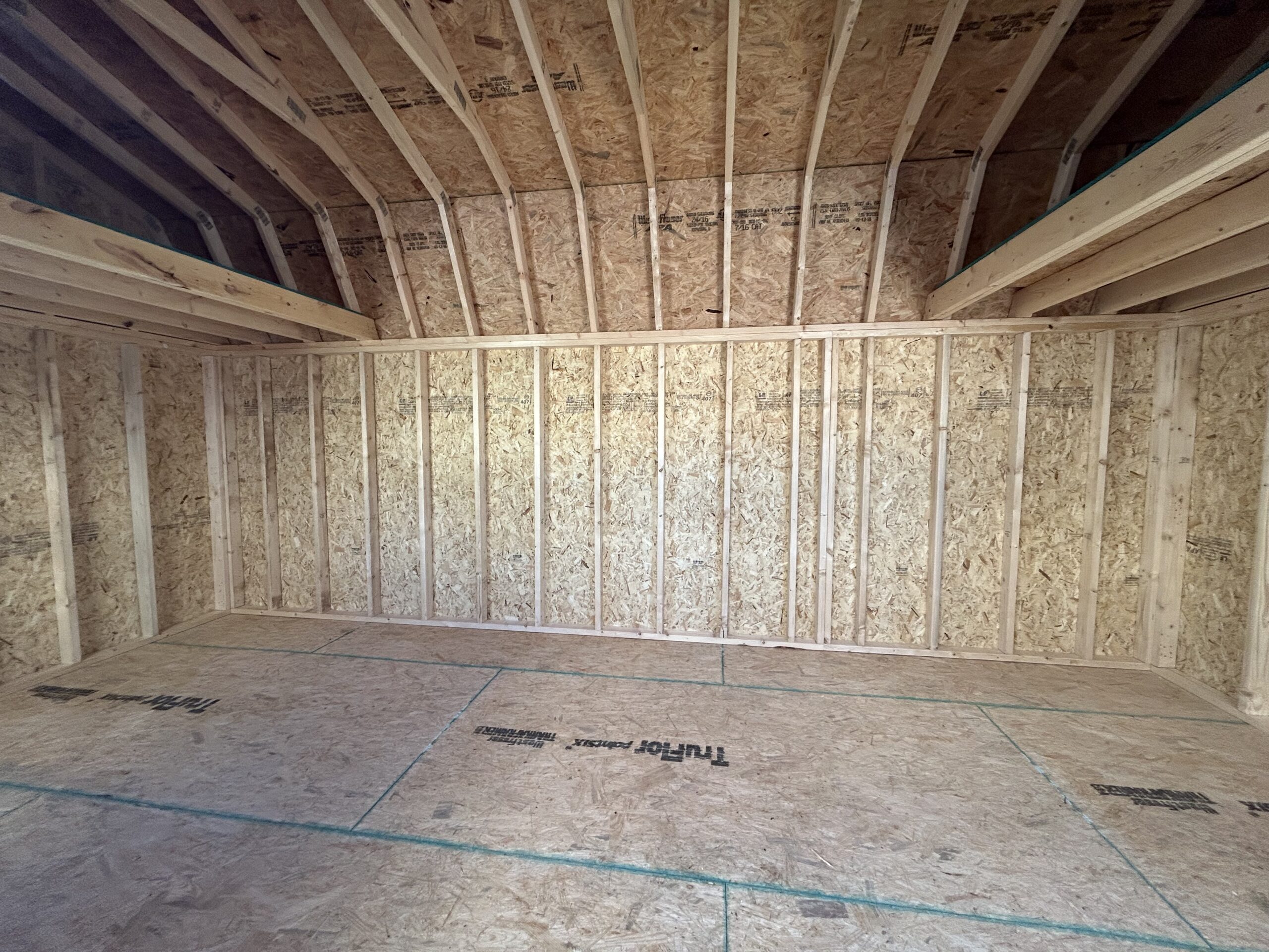 Unfinished attic with exposed wooden studs and OSB plywood sheathing on walls and roof.