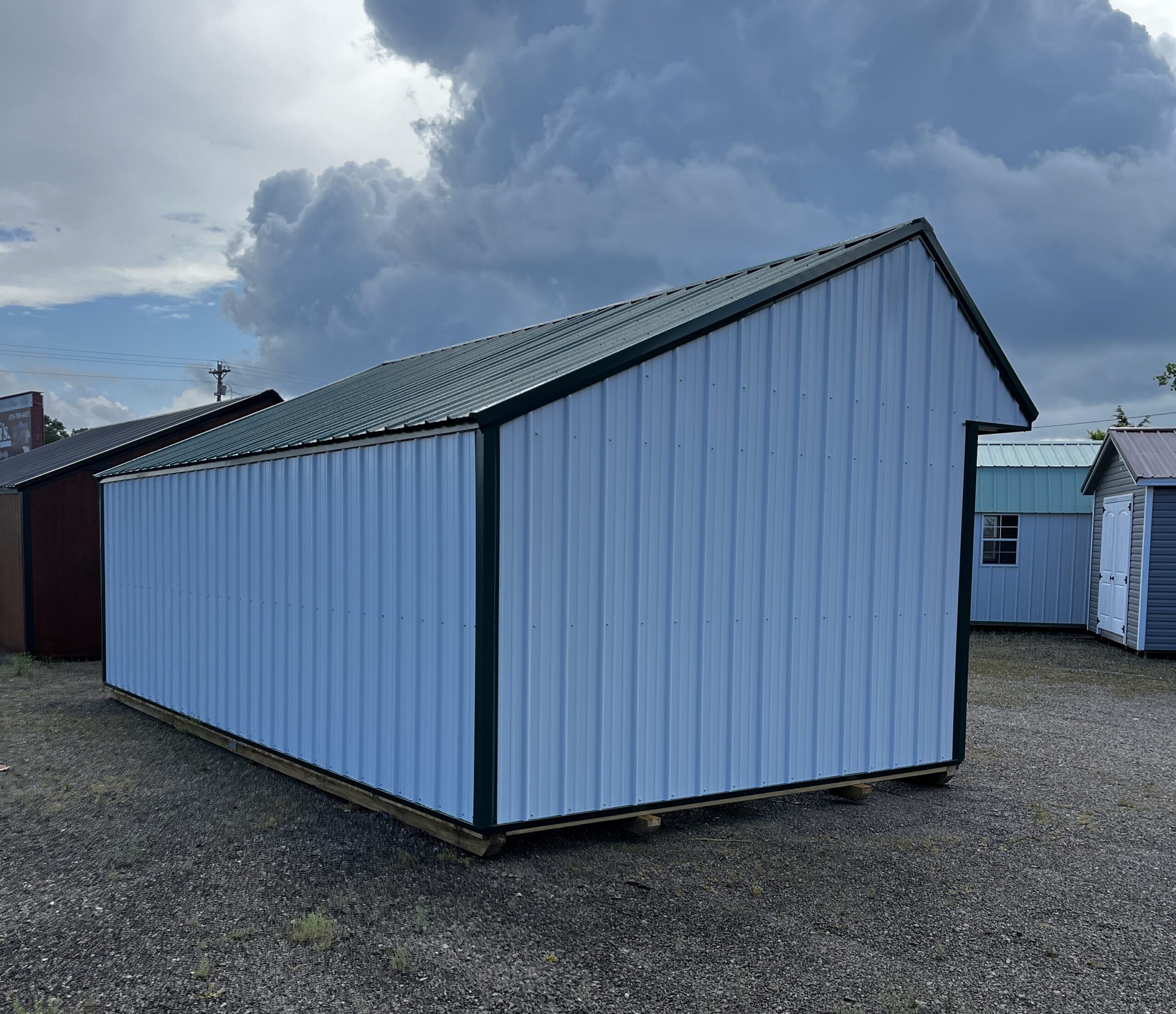 Blue corrugated metal warehouse wall with a slanted roof beneath a looming dark storm cloud on a cloudy day.